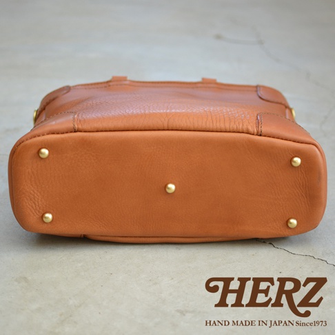 職人手作皮革Organ兩用商務托特包 G-61，採用溫潤的焦糖棕色皮革，包身底部有五個金屬腳釘，展現精緻工藝。