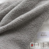 一條觸感柔軟的灰色今治浴巾，材質為純棉，表面有細緻的毛圈紋理，部分區域有摺疊效果，右下角可見品牌標籤「hiorie」及「MADE IN JAPAN」字樣，以及中文「日本桃雪」。