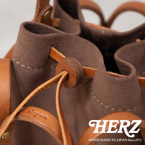 HERZ 職人手作皮革Organ編織水桶包，特寫展示咖啡色絨面內裡與棕色皮革束繩的細節