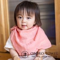 一位可愛的寶寶，臉部特寫，身穿粉紅色三層紗純棉寶寶裹身毯，材質輕柔。