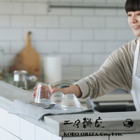 灰色棉麻混紡拭巾，上面放著一個玻璃杯和兩個小碗，以及一把銀色湯匙和叉子。