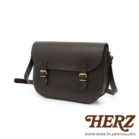 黑色皮革經典馬鞍包，附有兩個金色搭扣和可調式肩帶，設計簡約。