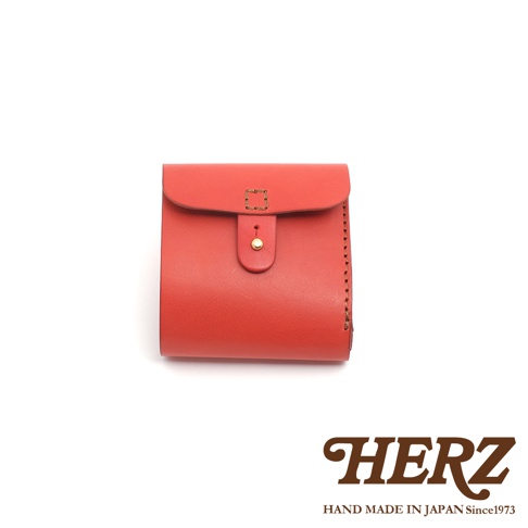 橘紅色皮革製成的二折式短夾，採用原子釦開合設計，側邊有手工縫線細節，風格簡約。