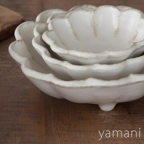 三個疊放的白色美濃燒沙拉盤，擁有花瓣狀的邊緣和復古的粉引紋理，盤底有三個小支腳，置於木質桌面。