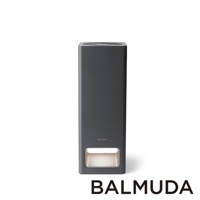 The Pure 空氣清淨機，深灰色，長方形直立式設計，頂部有風扇散熱孔，前方下方設有一個方形進氣口，內部為白色濾網，機身中央有 BALMUDA 品牌標誌。