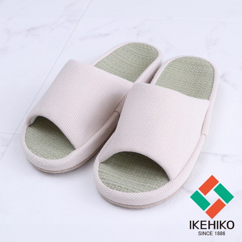 一雙淺米色藺草透氣室內拖鞋，鞋面織紋細緻，鞋底嵌入綠色藺草編織墊，設計簡約，適合居家穿著。