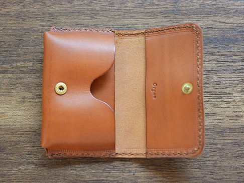 職人手作皮革Organ名片夾，採用棕色皮革製成，擁有兩個隔層，並以金色按扣固定，整體呈現簡約質樸的風格。