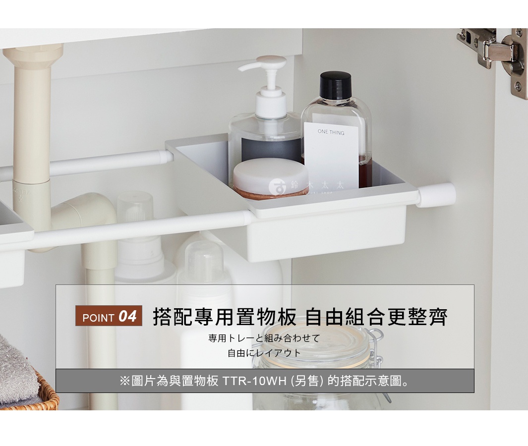 安裝於櫥櫃下方的白色長方形收納盒，懸掛於兩根平行的白色伸縮桿之間，盒內裝有瓶裝盥洗用品及保養品，盒身設計簡約，展示如何透過搭配專用置物板來整理居家空間，適合用於洗手台或流理台下方收納，圖片中央標註重點資訊說明可自由組合並整齊排列。