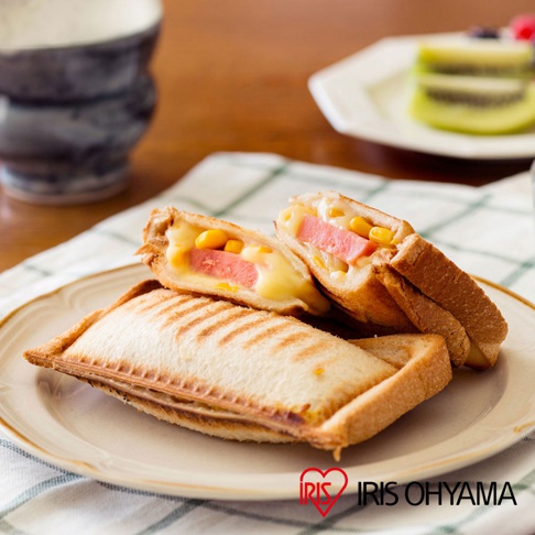 熱壓三明治夾烤盤 NGHS-DG，烤盤呈長方形，烤出金黃色澤並帶有烤痕，內含香腸、玉米粒與融化起司。