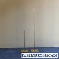 兩個黃銅一輪花器/燈具展示架，一個較高，一個較矮，均有方形底座，立於深藍色地面上，背景為淺色牆面。