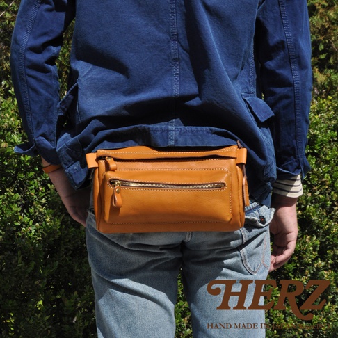 職人手作皮革兩用腰掛斜背包，採用棕褐色皮革製成，正面有一個拉鍊主袋和一個外部拉鍊小袋，可作為腰包或斜背包使用。