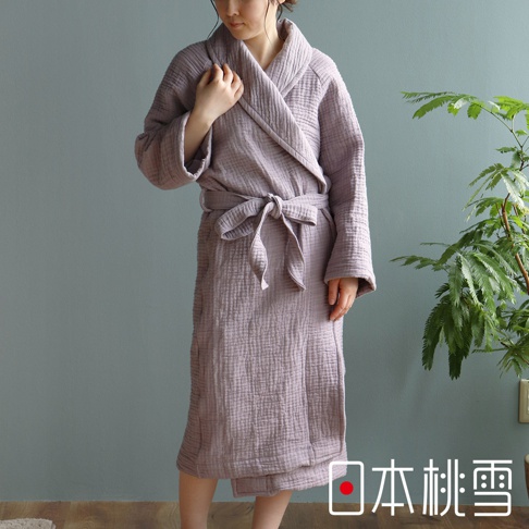 穿著一件淺紫色雙面紗布立體織紋輕質浴袍，附有綁帶，垂墜至小腿，搭配垂墜式領口和長袖。