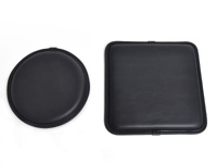 兩個黑色皮革坐墊，一個圓形，一個方形，均採用職人手作工藝，邊緣縫線精緻，材質光滑。