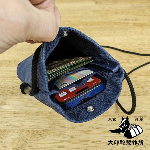 深藍色刺子織手機包，內部裝有手機、錢包及卡片。