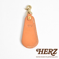 職人手作皮革隨身金屬鞋拔，淺棕色皮革，搭配黃銅色金屬扣環，鞋拔尖端有品牌壓紋「HERZ MADE IN JAPAN」。