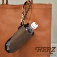 職人手作深棕色皮革Organ水壺套，附有長掛繩和金屬扣環，可掛於同色系皮革托特包上，中間裝有一瓶透明塑膠水瓶。