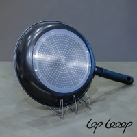 銀色不鏽鋼砧板架，支架呈現三角形結構，穩固支撐著黑色鍋底帶有圓形紋路的鍋具。