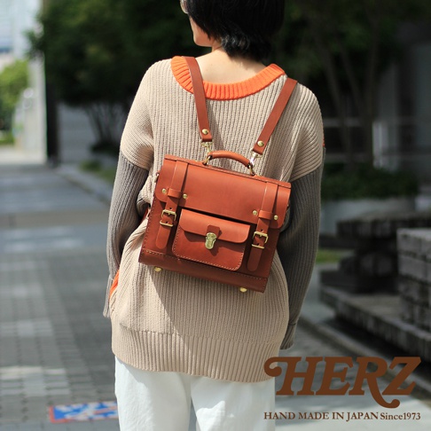 職人手作皮革學院風三用迷你後背包，採用經典棕色皮革製成，設有可調節肩帶、頂部提把、金屬鎖扣和前置口袋，風格復古且實用。