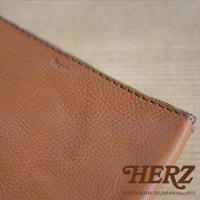 職人手作皮革Organ拉鍊式小物收納袋，淺棕色皮革，表面有細緻紋理，邊緣以深色縫線車縫，右下角有「HERZ」品牌標誌。