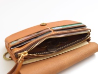 職人手作皮革旅行用多層次收納長夾，淺棕色皮革材質，拉鍊開闔，內有信用卡、硬幣及紙鈔隔層，金色拉鍊及銅製掛環。