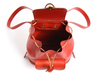 紅色皮革迷你後背包，頂部翻蓋敞開，露出內部空間，兩側有抽繩設計，正面有一個小隔層，配有皮革束帶和金屬扣。