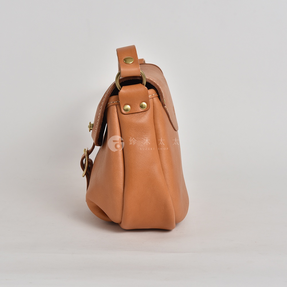 日本HERZ職人手作皮革休閒旅行馬鞍包，側面視角，淺棕色，附有金屬扣環和背帶。