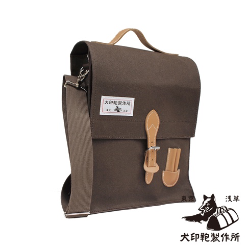深棕色純綿帆布製成，直立式側背包，配有淺棕色皮革翻蓋、扣帶和提把，可調節的帆布肩帶，有品牌標籤。