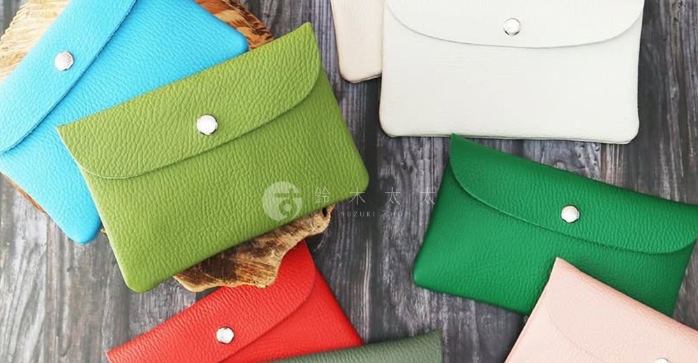 多個顏色（天藍、淺綠、白色、鮮綠、紅色、粉色）的皮革手拿包，帶有銀色按扣。