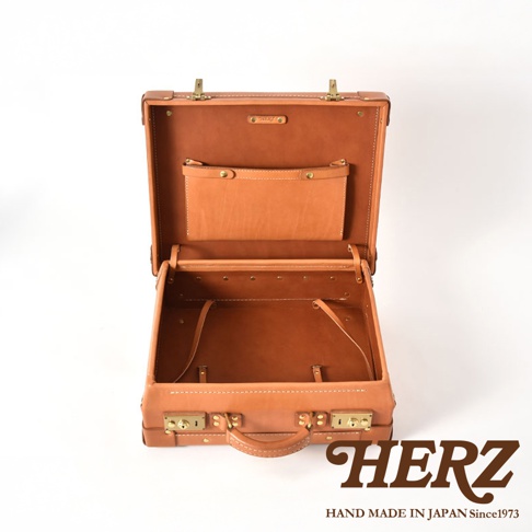 開放式棕褐色皮革手提行李箱，內部有隔層和固定帶，外部有兩個鎖扣和一個提把。