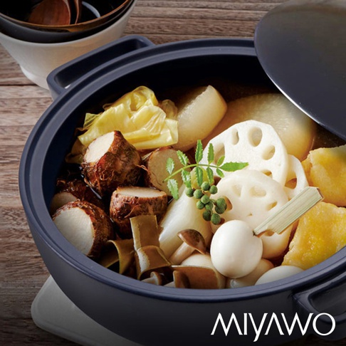 海軍藍色的陶土湯鍋盛滿燉煮的食材，包括芋頭、白蘿蔔、蓮藕、香菇、白菜及鵪鶉蛋，鍋蓋部分開啟，露出部分湯鍋內部。