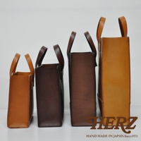 四個不同尺寸的職人手作皮革直式托特包，由左至右分別為淺棕色、深棕色、咖啡色與橘棕色，包款皆為直立式設計，搭配提把。