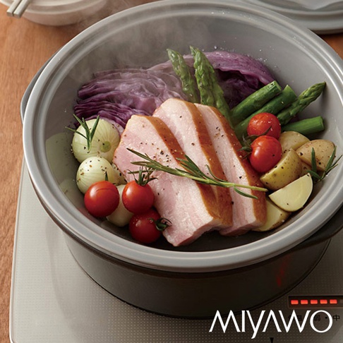 深灰陶土蒸盤內盛放著切片五花肉、蘆筍、小番茄、馬鈴薯塊、洋蔥和紫甘藍，散發蒸氣。