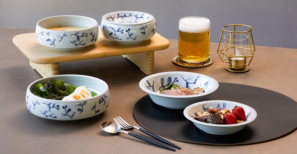 波佐見燒藍花紋六件式碗盤組，包含帶有藍色植物圖案的白色陶瓷碗盤，其中一個碗內盛有沙拉和水煮蛋，另一碗裝有肉類和蔬菜，還有一個小碗盛有堅果、巧克力和草莓。