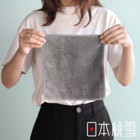 一個女人拿著一塊灰色的毛巾，上面有日文文字「日本桃雪」。