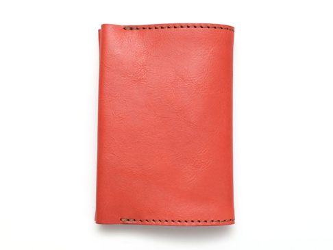 橘紅色皮革翻蓋記事本書套，有手工縫線細節。