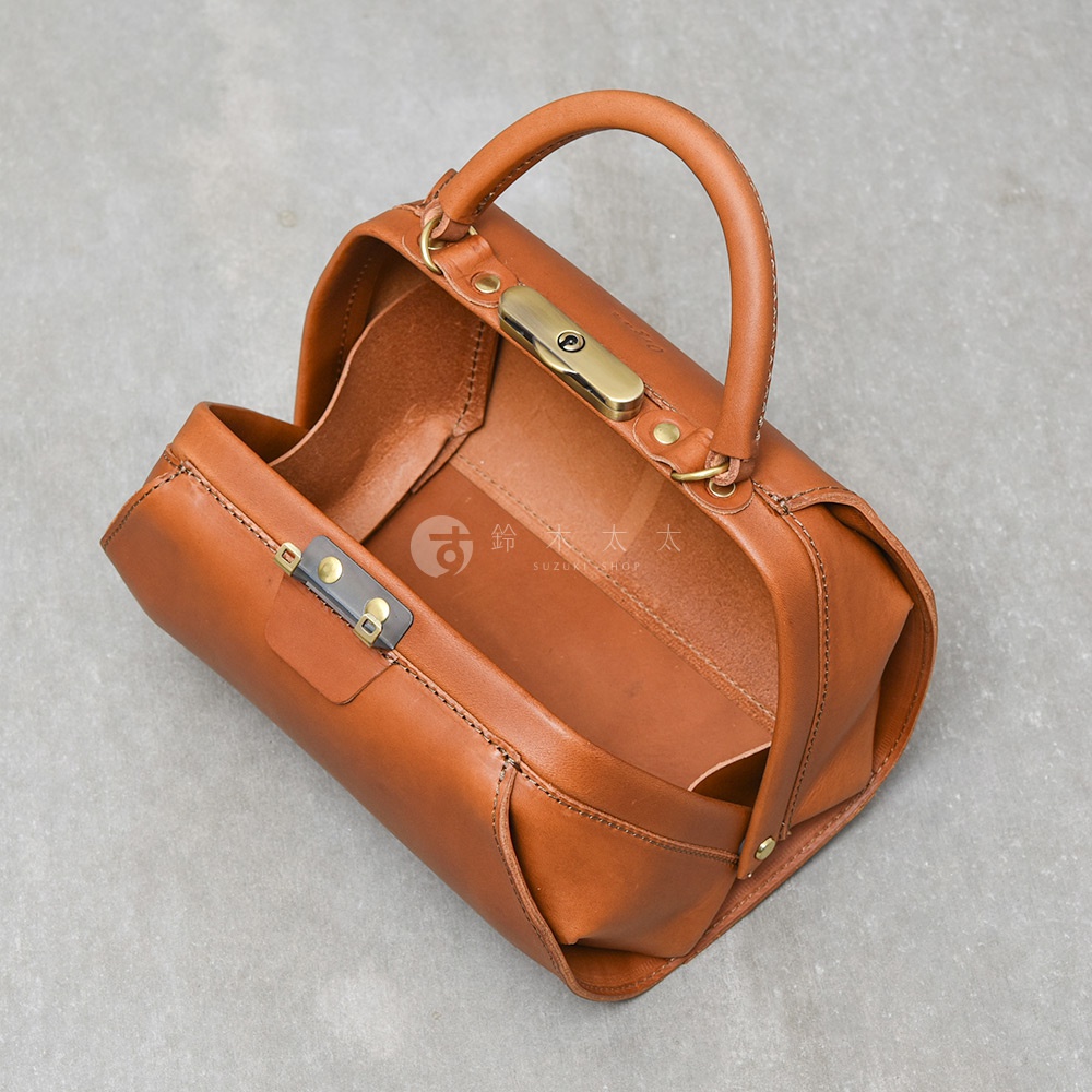 棕色皮革手提包，頂部有圓形手柄，側面有金色金屬鎖扣，包身開口，露出皮革內襯。