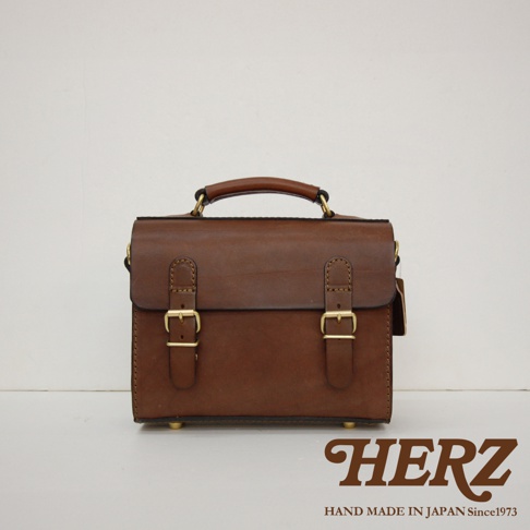 棕色皮革迷你手提包，配有兩個金色搭扣和一個頂部提把，簡約設計。