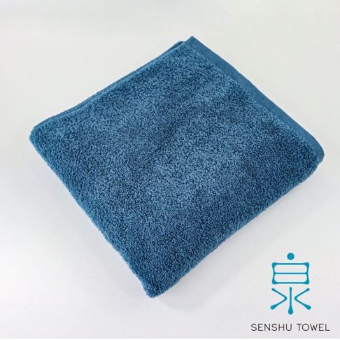 深藍色長纖浴巾，質地柔軟，表面有細緻的絨毛，邊緣有整齊的縫線。