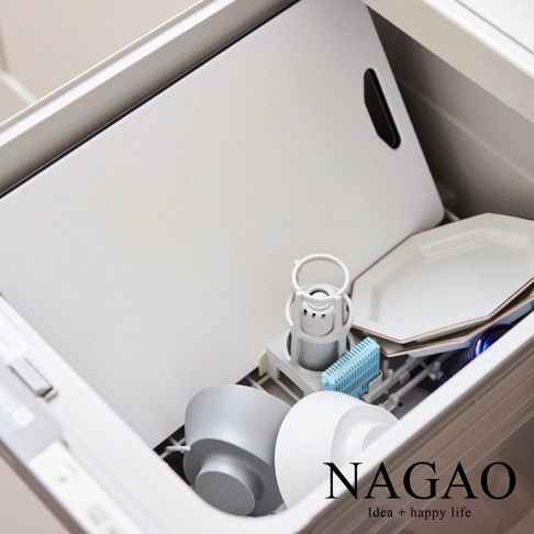 白色雙面抗菌耐熱砧板，帶有黑色切口手柄，放置於洗碗機內，旁邊有灰色和白色碗盤，以及藍色濾網。