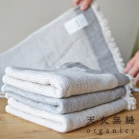 堆疊四條 HEATHER 有機混紡棉浴巾，呈現不同深淺的灰色和白色條紋，織物質感明顯，邊緣飾有流蘇。