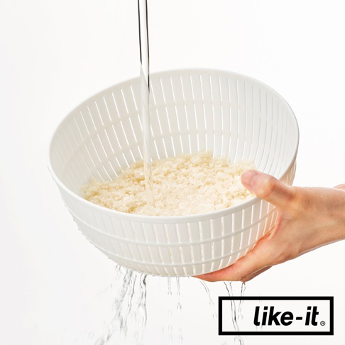 白色簡約雙層塑膠瀝水籃，盛有米粒，水從上方流入並從籃子下方瀝出，有手持著籃子。