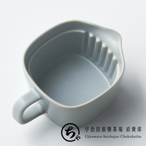 這是一個從上方視角拍攝的灰色美濃燒茶壺，外觀呈現圓潤方形，設計簡約。茶壺內側邊緣帶有溝槽設計，左側設有把手，右側則有小巧的壺嘴。圖片右下方標有宇治田原製茶場的圓形商標以及對應的中英文名稱。