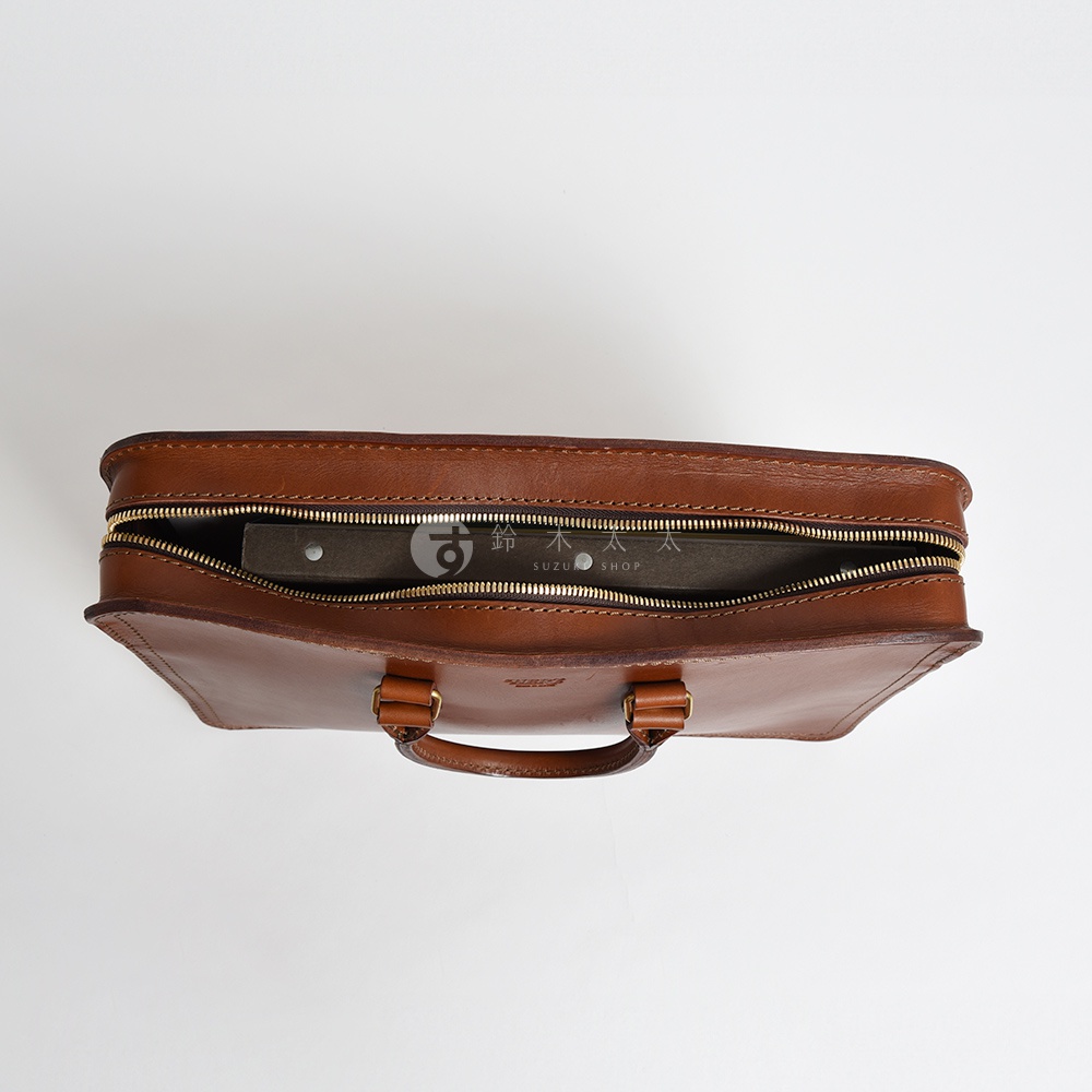 棕色皮革手提公事包，頂部拉鍊半開，露出內部文件，包身有兩個提把，採用金屬拉鍊。