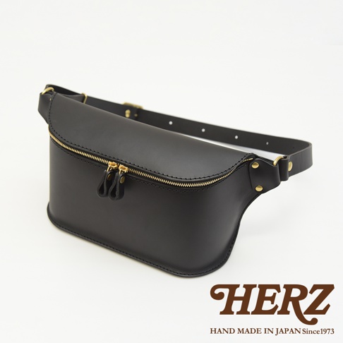 黑色職人手作皮革立體斜背包，設有雙拉鍊開口，搭配金色拉鍊頭及扣環，皮質堅韌，設計簡約。