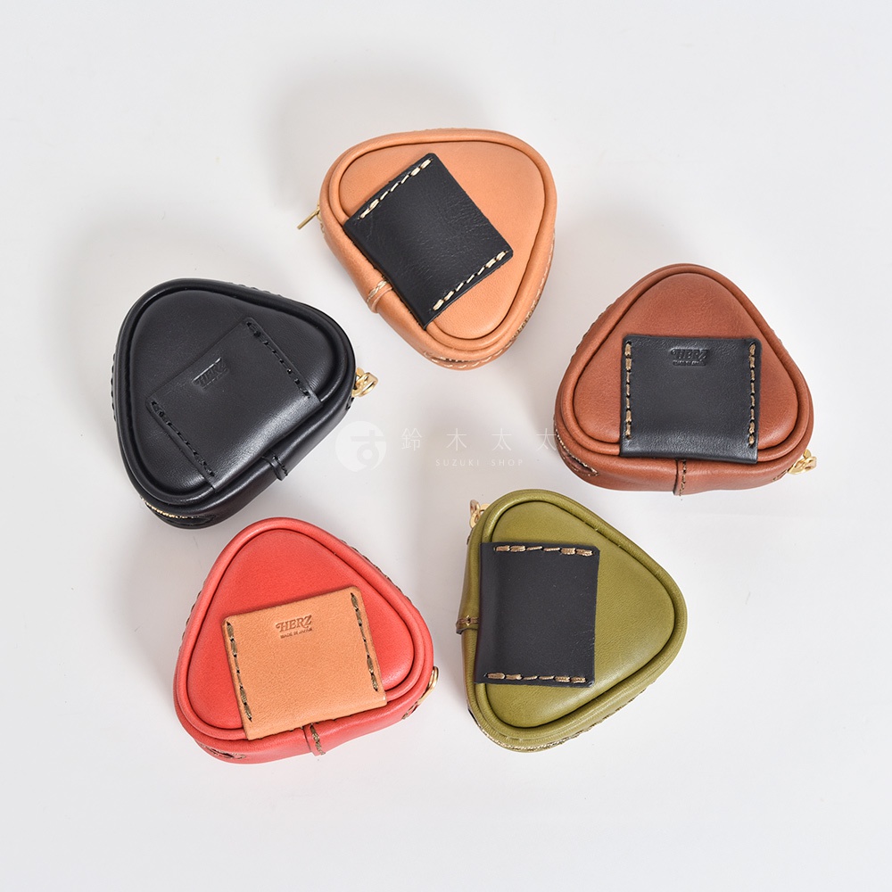 五個職人手作皮革小物收納包，皆為三角飯糰造型。顏色包含黑色、棕色、紅色、橘色與綠色。包包材質為皮革，並以手工縫線裝飾，部分款式側面有拉鍊。