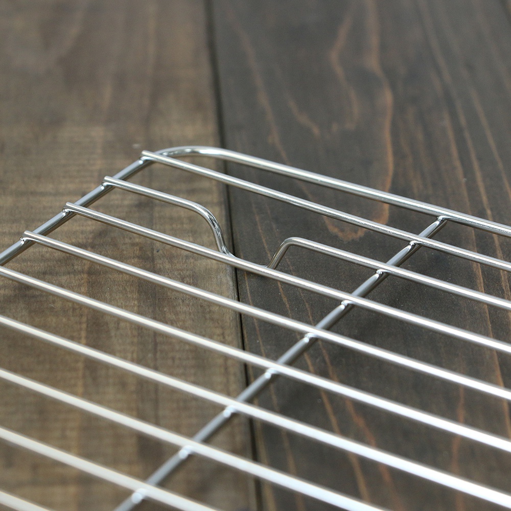 23公分方形不鏽鋼瀝油架，由銀色金屬網格構成，網格間距均勻，邊緣為圓弧形設計，放置於深色木紋背景上。