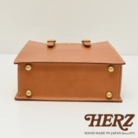 職人手作皮革商務用紙袋托特包，淺棕色，方形設計，頂部有兩個銅扣帶，側面有四個銅質鉚釘，縫線精緻。