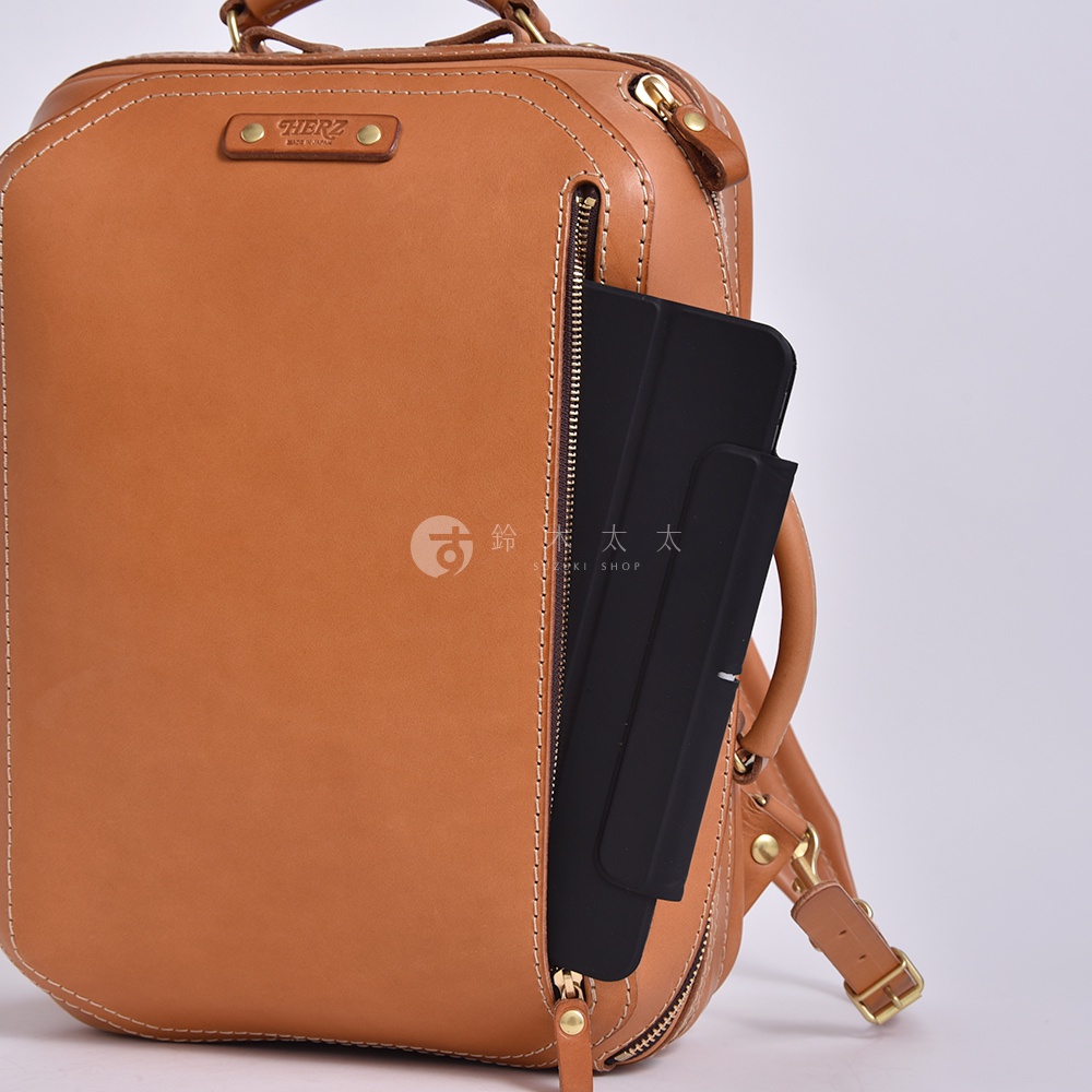 職人手作的淺棕色皮革兩用商務後背包，外觀簡潔，配有拉鍊隔層，可放入平板電腦。包身縫線精緻，材質為真皮。