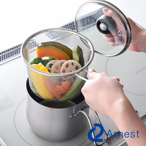 一個不鏽鋼鍋，鍋中裝有蔬菜，如南瓜、蓮藕、花椰菜、蘆筍和胡蘿蔔，並放置在一個網狀瀝水籃中。一只手正將瀝水籃從鍋中取出，另一只手準備蓋上玻璃鍋蓋。