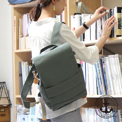 loiter高島帆布前蓋式背包，採用淺灰綠色帆布材質，設計簡約，前蓋有雙層口袋，側邊有置物袋，附有木製船錨吊飾。